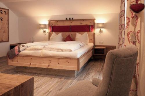 Schlafzimmer mit einem großen Bett mit einem Kopfteil aus Holz in der Unterkunft Pension Alpenblick in Pfronten