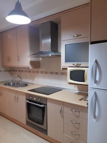 a kitchen with a stove and a microwave and a refrigerator at ALOJAMIENTO ARGOS , junto al CASCO HISTORICO DE CEHEGIN y a 6 kilometros DE CARAVACA DE LA CRUZ in Cehegín