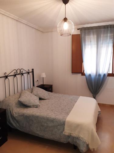 1 dormitorio con cama y lámpara de araña en ALOJAMIENTO ARGOS , junto al CASCO HISTORICO DE CEHEGIN y a 6 kilometros DE CARAVACA DE LA CRUZ en Cehegín