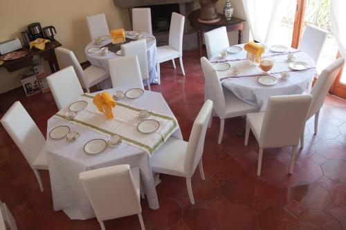 una sala da pranzo con tavoli bianchi e sedie bianche di Domus in Viridi a Roma