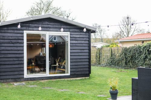 a black shed with a window in a yard at Stijlvol ingerichte bungalow aan de Westerschelde in Baarland