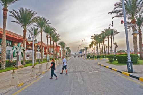 two people walking down a street with palm trees at Modern Mountain View on The Touristic Promenade in Hurghada