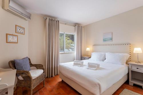 a bedroom with a large white bed and a chair at Townhouse Seraphina in Vale do Lobo