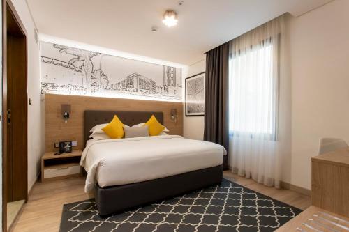 ein Hotelzimmer mit einem großen Bett mit gelben Kissen in der Unterkunft Cindyan Apartments by The Quarter in Khobar