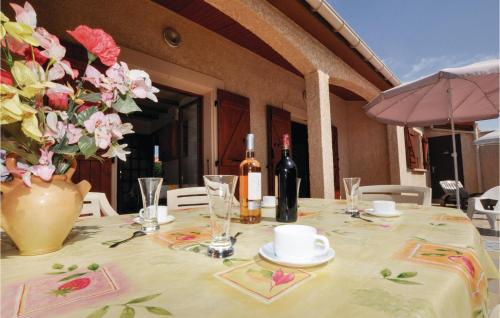 a table with a vase of flowers and wine bottles at Two-Bedroom Holiday Home In Sainte Marie Plage in Sainte-Marie-Plage