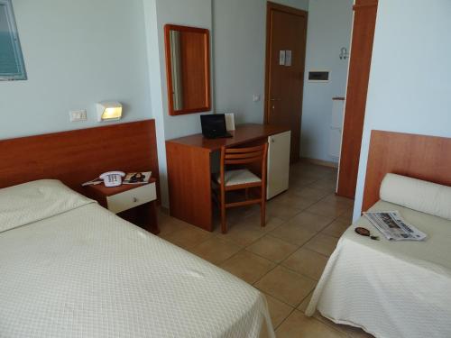 a room with two beds and a desk with a computer at Hotel Sole E Mare in Lido di Camaiore