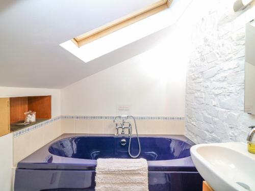 y baño con bañera azul y lavamanos. en Kingfisher Cottage, en Holsworthy