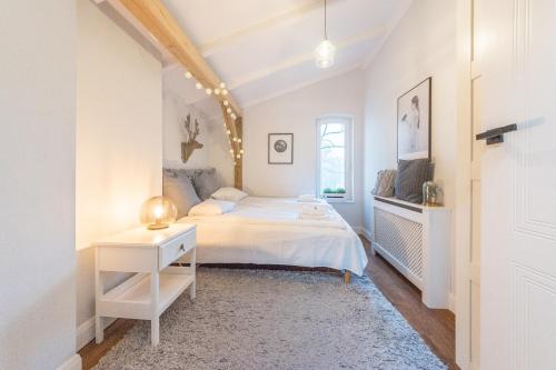 Dormitorio blanco con cama y mesa en Dom & House - Apartment Loft Supreme, en Sopot