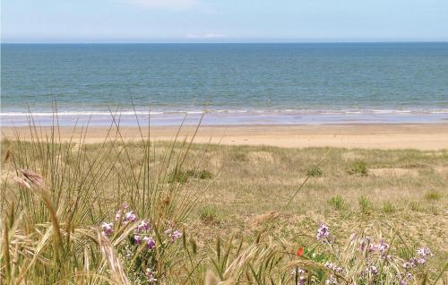 une plage de sable avec des fleurs violettes et l'océan dans l'établissement Two-Bedroom Holiday Home In St Michel Chef Chef, à Saint-Michel-Chef-Chef
