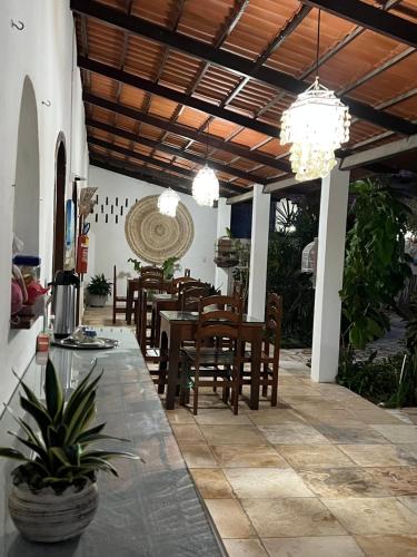 a dining room with a table and chairs and chandeliers at Pousada Califórnia Tia Lia in Paracuru