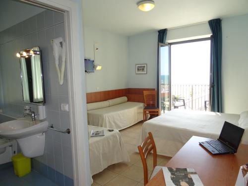 a hotel room with a bedroom with a bed and a sink at Hotel Sole E Mare in Lido di Camaiore