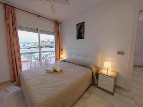 Apartamentos Las Rosas de Capistrano في نيرخا: غرفة نوم بسرير ونافذة كبيرة