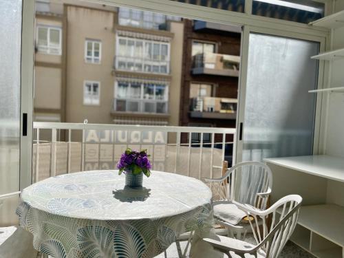 una mesa con un jarrón de flores púrpuras en el balcón en Calle Gambo Apartment, en Benidorm