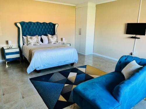 a bedroom with a blue bed and a couch at Aaron's Nest Bed and Breakfast in Ladysmith