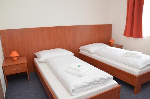2 camas en una habitación con sábanas blancas y toallas en Hotel Růženy, en Hustopeče