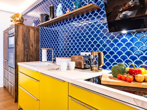 a kitchen with yellow cabinets and blue tiles at Ostseeresidenz Lidia mit Terrasse und Meerblick in Sassnitz