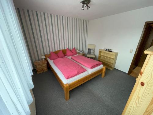 - une chambre avec un grand lit et des oreillers roses dans l'établissement Ferienwohnung in Frielendorf, à Frielendorf