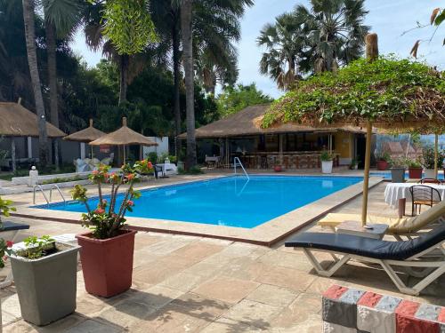 a pool at a resort with a chair and an umbrella at Calabash Residence Apartments in Kotu