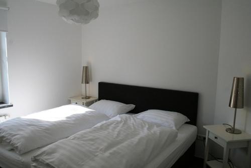 um quarto com uma cama com lençóis brancos e 2 candeeiros em Am Finkenbusch aan de skipiste em Willingen