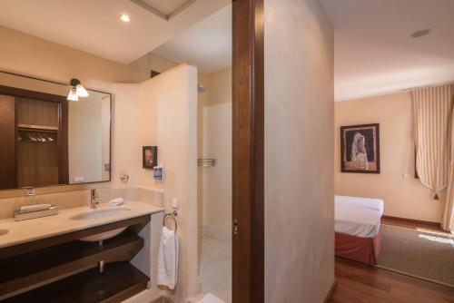 een badkamer met een wastafel, een spiegel en een bed bij Villa Lila in Benalup Casas Viejas