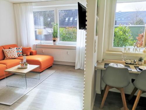 a living room with an orange couch and a table at Butze Ferienapartment in Büsum