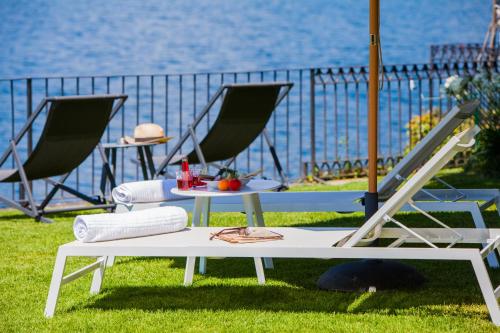 a table and chairs sitting on the grass near the water at Bifora65 flats and garden - Lakeview in Orta San Giulio