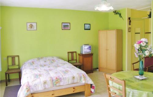 a bedroom with a bed and a table with a tv at Awesome Home In Quettehou With Kitchenette in Quettehou