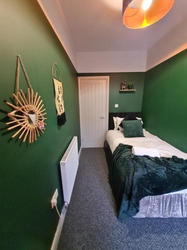 1 dormitorio con paredes verdes y 2 camas en 4 BR Luxury House. Bike Park Wales. Secure Bike Store. Brecon Beacons, en Dowlais