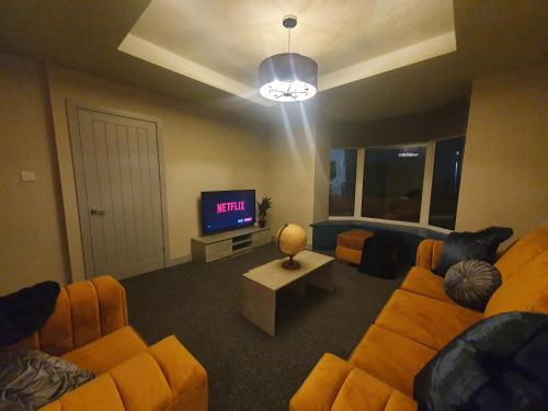 a living room with two couches and a tv at 4 BR Luxury House. Bike Park Wales. Secure Bike Store. Brecon Beacons in Dowlais