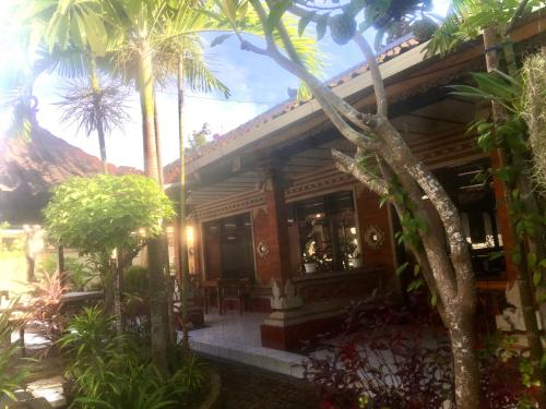 a house with palm trees in front of it at Lestari Homestay in Sanur