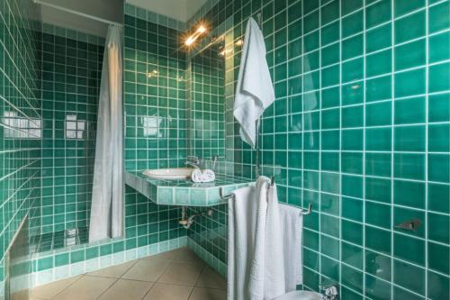 a green tiled bathroom with a sink and a mirror at Baia Del Faro in Palau