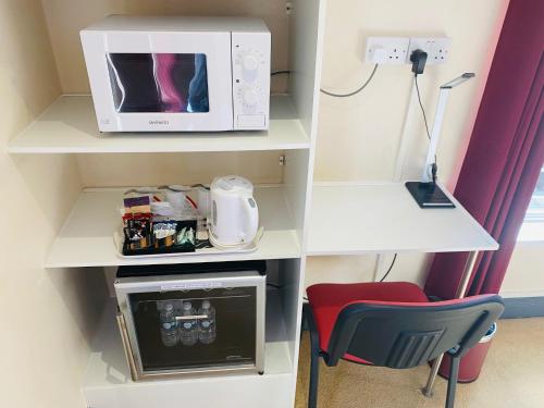 a kitchen with a microwave and a chair in a room at The Railway Sleeper Lodge in Colchester