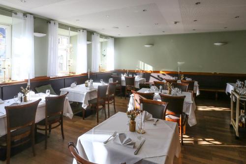 a dining room with white tables and chairs and windows at Hotel Lutz in Rain