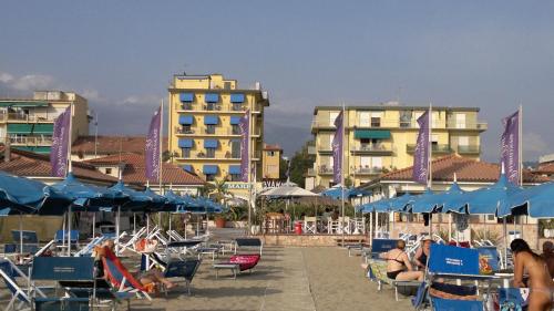 a group of people sitting in lawn chairs at a beach at Hotel Sole E Mare in Lido di Camaiore