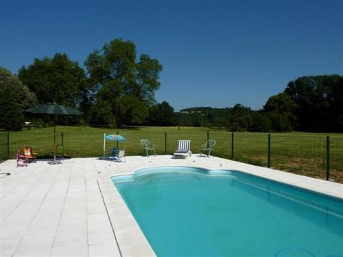 a swimming pool with chairs and umbrellas next to a field at Domaine de Lalande in Vénès