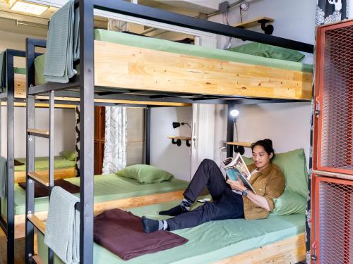 a man reading a book in a bunk bed room at Hybrit hostel&cafe in Hat Yai