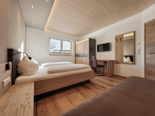 a bedroom with a large bed and a desk at Gästehaus Sonne in Bichlbach