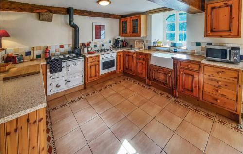 - une grande cuisine avec des placards en bois et des appareils blancs dans l'établissement La Grande Chaise, à Bonnemain