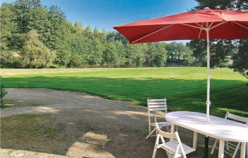a table with a red umbrella and two chairs under it at Nice Home In La Chapelle Hermier in La Chapelle-Hermier