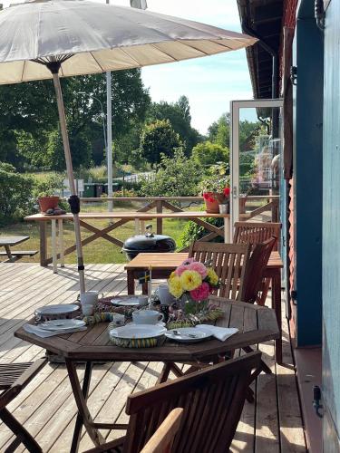 a wooden table with flowers on a deck with an umbrella at STF Baskemölla Hostel in Simrishamn