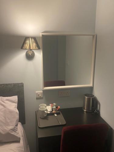 a bedroom with a bed and a table with a mirror at Comus Inn in Selby