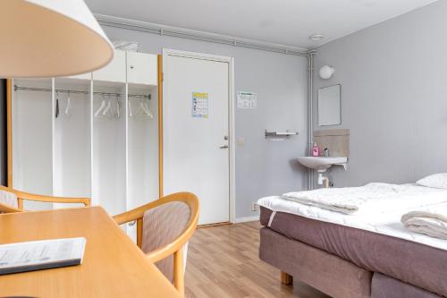 a bedroom with a bed and a table and a sink at STF Baskemölla Hostel in Simrishamn