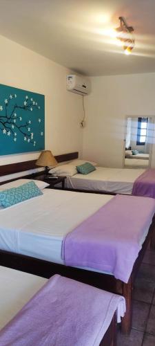 a group of three beds in a room at Hotel Pousada Laje de Itauna in Saquarema