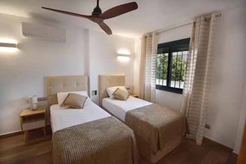 Un dormitorio con dos camas y un ventilador de techo. en Urb Pueblo del Parque, Luxury 2 bedroom apartment. Fantastic central location., en Benalmádena