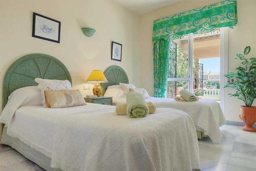 フエンヒロラにあるLas Palmeras Colinaのベッドルーム1室(白いシーツが備わるベッド2台、窓付)