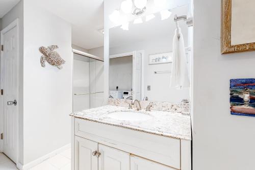 a white bathroom with a sink and a mirror at Olde Homestead Hideaway in Harwich