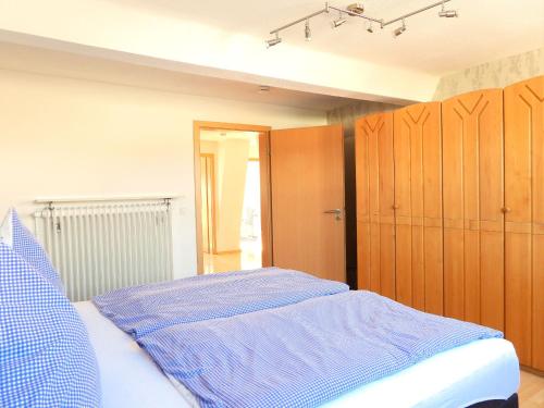 um quarto com uma cama com lençóis azuis e armários de madeira em Weingut Michael Grünewald & Söhne em Bingen am Rhein