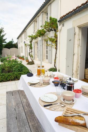 une table blanche avec des assiettes de nourriture dans l'établissement A l'ombre du figuier, à Longèves