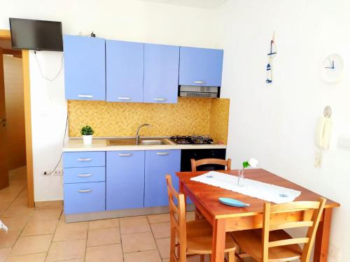レウカにあるCasa Vacanze salentoのキッチン(青いキャビネット、木製テーブル付)
