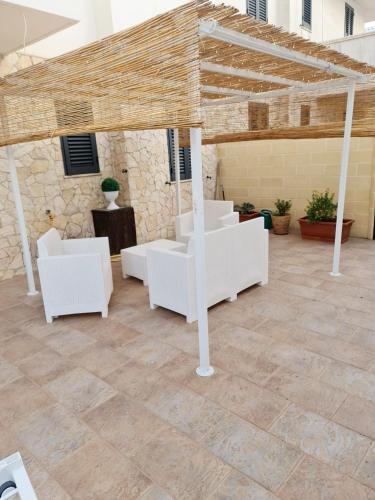 レウカにあるCasa Vacanze salentoの石壁のパティオ(白い家具付)